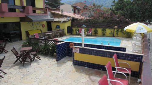 a swimming pool with chairs and a table and an umbrella at Pousada Casa na Praia in Ubatuba
