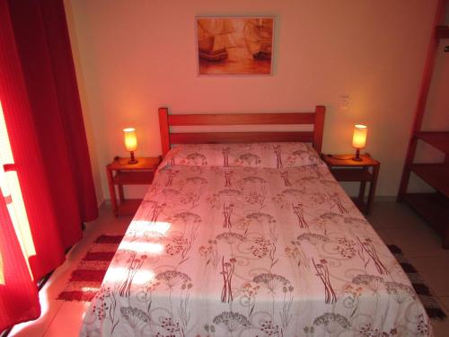 a bedroom with a bed with two lamps on two tables at Pousada Casa na Praia in Ubatuba
