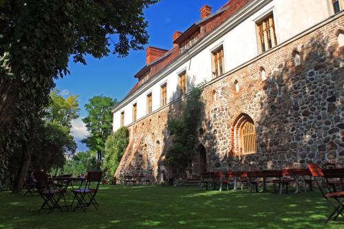 ein großes Steingebäude mit Tischen und Stühlen im Gras in der Unterkunft Klasztor Cedynia Hotel in Cedynia