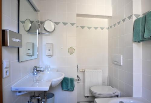 a white bathroom with a sink and a toilet at Hotel Alpenblick Garni in Überlingen