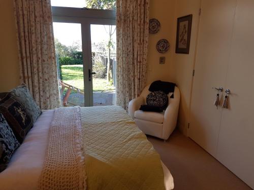 1 dormitorio con 1 cama, 1 silla y 1 ventana en The Glen Taupo en Taupo