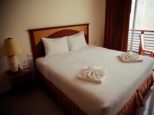 a bedroom with a large bed with two towels on it at The Orchid House - SHA Extra Plus in Kata Beach