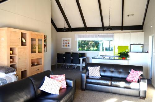 a living room with a leather couch and a kitchen at A Touch of Tuscany at Hillsborough in New Plymouth