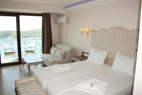 a bedroom with a large white bed and a living room at Palatino Hotel in Parga