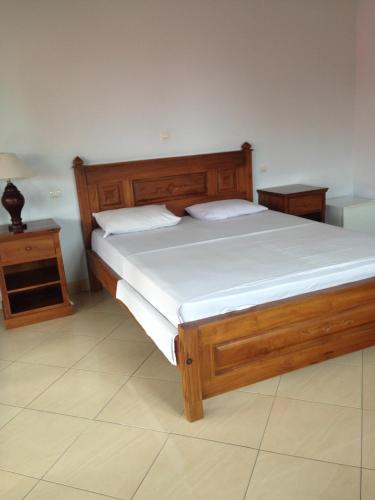 a bedroom with a large wooden bed with white sheets at Gede Homestay in Lovina