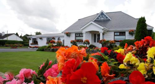 a white house with flowers in front of it at Rosemount B&B in Dundalk