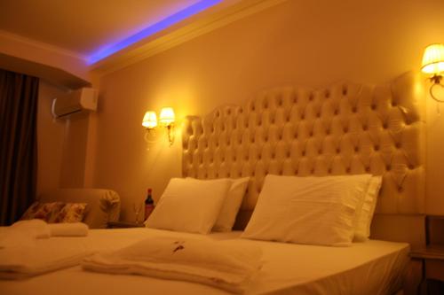 a bedroom with a white bed with a large headboard at Palatino Hotel in Parga