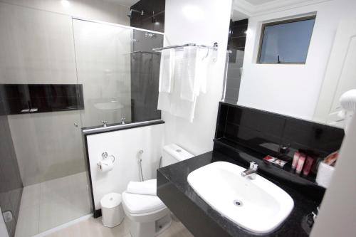 uma casa de banho com um lavatório, um chuveiro e um WC. em Hotel Bhally em Balneário Camboriú