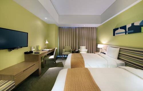 a hotel room with two beds and a flat screen tv at Park City Hotel - Luzhou Taipei in Taipei