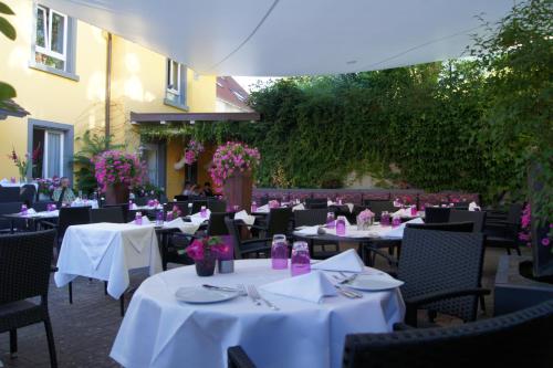 Un restaurante con mesas y sillas blancas y flores. en Genusshotel Krone & Roadtrips bei Basel, en Inzlingen