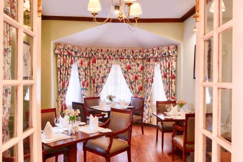 a dining room with tables and chairs and windows at Jetwing Oatlands Bungalow in Nuwara Eliya