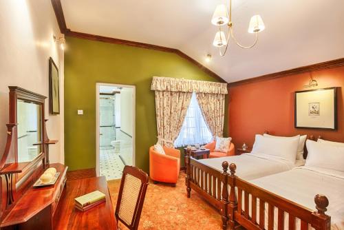 a bedroom with a bed and a desk and a chair at Jetwing Oatlands Bungalow in Nuwara Eliya