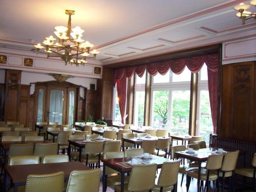 una sala da pranzo con tavoli, sedie e lampadario a braccio di Hotel Manhattan a Bruxelles