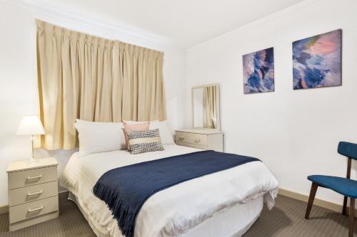 1 dormitorio con 1 cama y 1 silla azul en South Perth Executive Apartment, en Perth