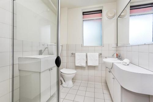 a white bathroom with a toilet and a sink at South Perth Executive Apartment in Perth