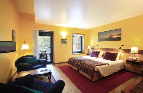 a hotel room with a bed and a chair at Aldeia da Fonte Hotel in Lajes do Pico