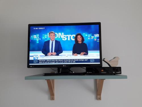 a flat screen tv with two people on it at Les Appartements du 104 in Saint-Jean-de-Monts