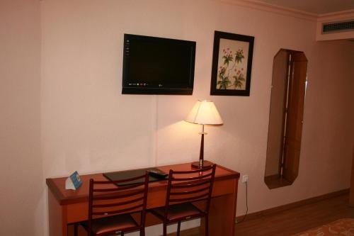 a room with a desk with two chairs and a lamp at Hotel Cabañas in Puertollano