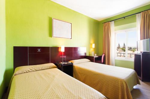 a hotel room with two beds and a window at Hotel Carlos V in Granada