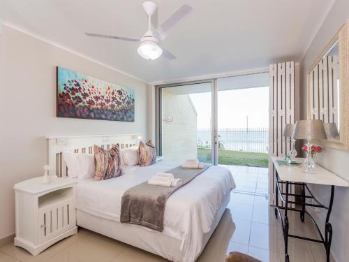 a white bedroom with a bed and a large window at 3 Driftwood in Ballito