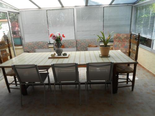 a dining room table with chairs and a vase with flowers at Maison Monica Exeptionnel-Jardin paysage ZEN in Coursan
