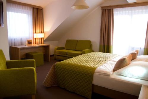 a hotel room with a bed and a chair at Altes Kurhaus Landhotel in Trabelsdorf
