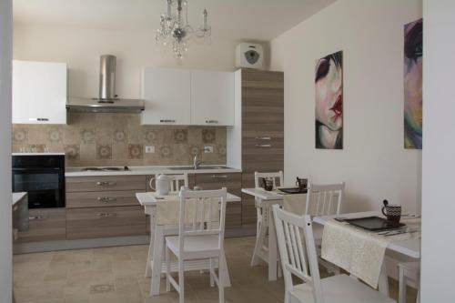 a kitchen with white cabinets and white chairs and a table at B&B Armonia in Montecosaro