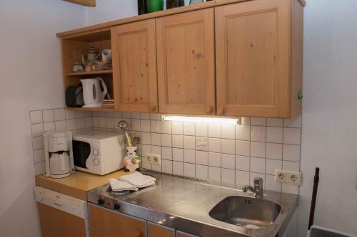 eine Küche mit einer Spüle und einer Mikrowelle in der Unterkunft Apartment Krabacher in Seefeld in Tirol