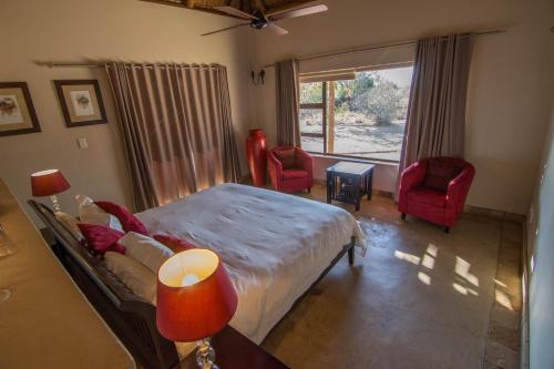 a bedroom with a bed and two chairs and a window at Zebula Golf Estate and Spa - Jackals Call 8 pax Moi Signature Luxury villa in Mabula