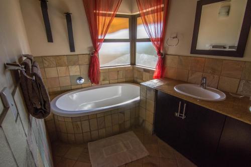 a bathroom with a tub and a sink at Zebula Golf Estate and Spa - Jackals Call 8 pax Moi Signature Luxury villa in Mabula
