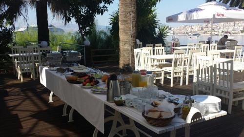 una mesa con comida en ella con sillas blancas y un Sidx de mesa en Hotel Magllara, en Sarandë