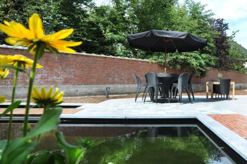 a table and chairs with an umbrella next to a pool at Charmehotel Villa Saporis in Hasselt