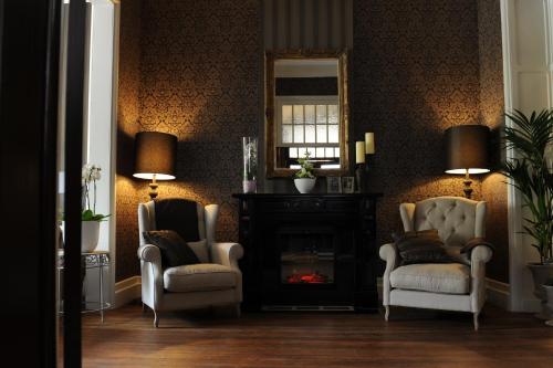 a living room with two chairs and a fireplace at Charmehotel Villa Saporis in Hasselt