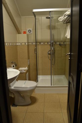 a bathroom with a shower and a toilet and a sink at Hotel Athos in Bucharest
