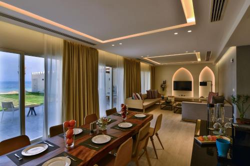 a dining room with a table and a living room at Sealine Beach, a Murwab Resort in Mesaieed