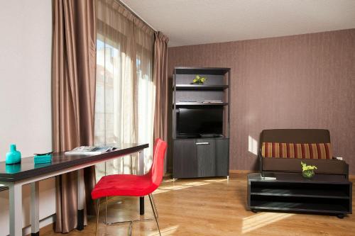 a living room with a desk and a red chair at Residhome Metz Lorraine in Metz