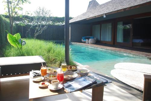 een dienblad met eten op een tafel naast een zwembad bij The Santai by LifestyleRetreats in Canggu