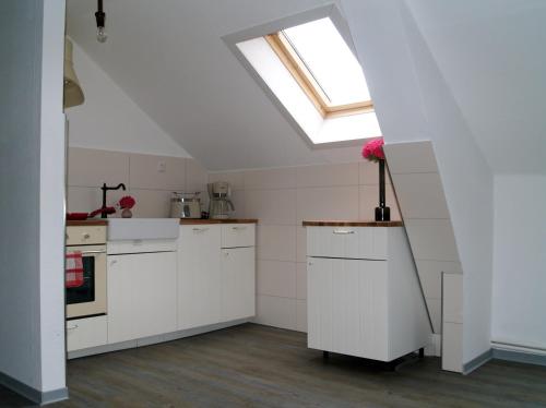 a kitchen with white cabinets and a skylight at Schleusenhof Ferienwohnung in Spieka-Neufeld
