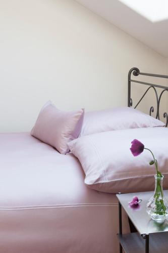 a bed with white sheets and a vase of flowers on a table at Landhaus 3 Birken in Landkern