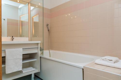 a bathroom with a tub and a sink and a shower at Résidence Odalys L'Ecrin des Neiges in Valmeinier