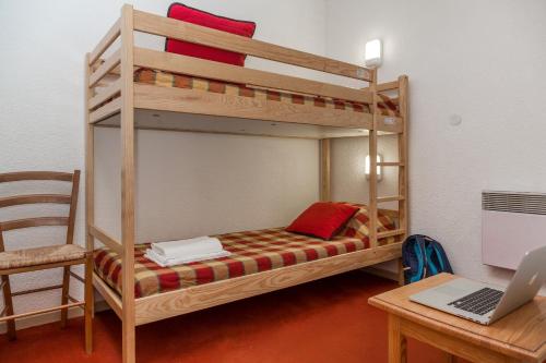 a room with two bunk beds and a desk with a laptop at Résidence Odalys L'Ecrin des Neiges in Valmeinier