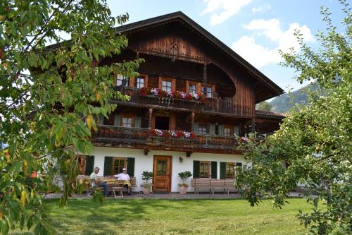 a house with people sitting at a table in front of it at Böglhof in Stumm