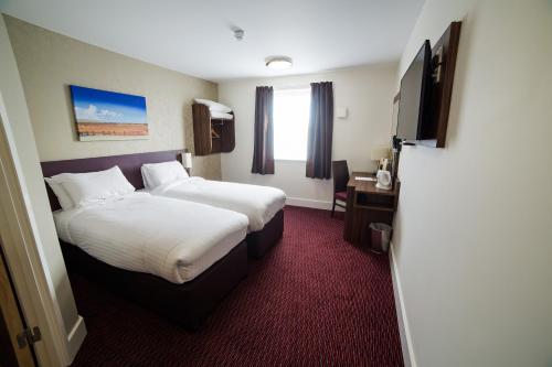 a hotel room with two beds and a flat screen tv at Red Squirrel, Stevenston by Marston's Inns in Stevenston