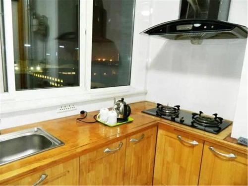 uma cozinha com um lavatório, um fogão e uma janela em Xi'an Helen Apartment em Xi'an