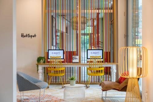 a room with yellow chairs and a table and a window at Capri by Fraser Berlin in Berlin
