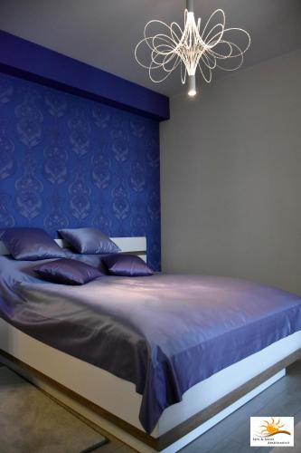 a bedroom with a bed with a blue wall at Apartament Sun & Sand Polanki in Kołobrzeg