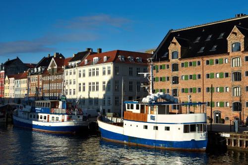 two boats docked in the water in front of buildings at 71 Nyhavn Hotel in Copenhagen