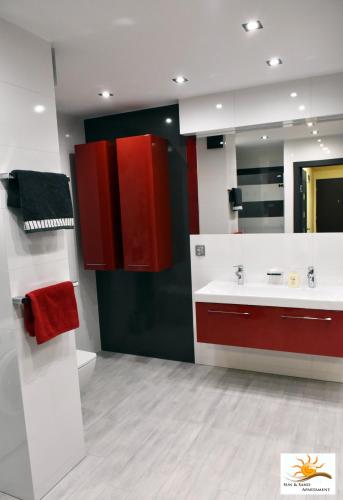 a bathroom with red cabinets and a sink at Apartament Sun & Sand Polanki in Kołobrzeg