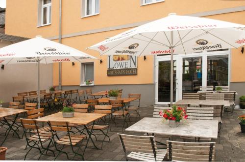un patio esterno con tavoli, sedie e ombrelloni di Hotel Restaurant Nassauer Löwen a Nassau