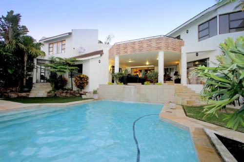 a swimming pool in front of a house at La Dolce Vita Umhlanga Guesthouse in Durban